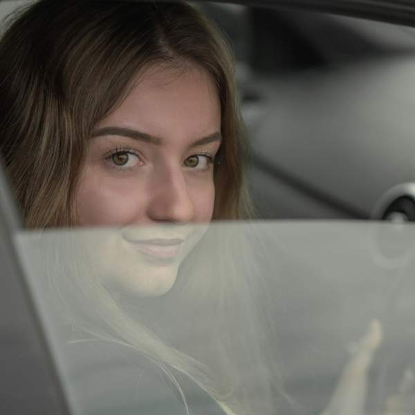 Photograph of a woman behind the wheel of an Audi, looking out of a slightly opened side window