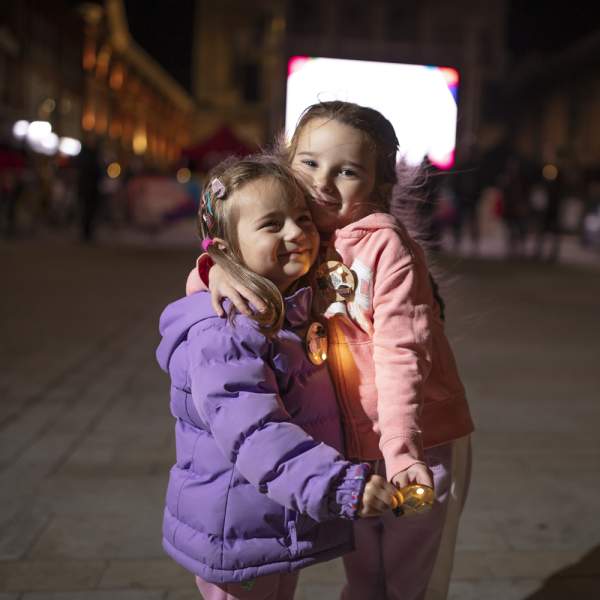 Two children embracing near a light installation