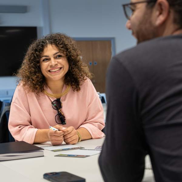 a close up of 2 people at a workshop talking and smiling