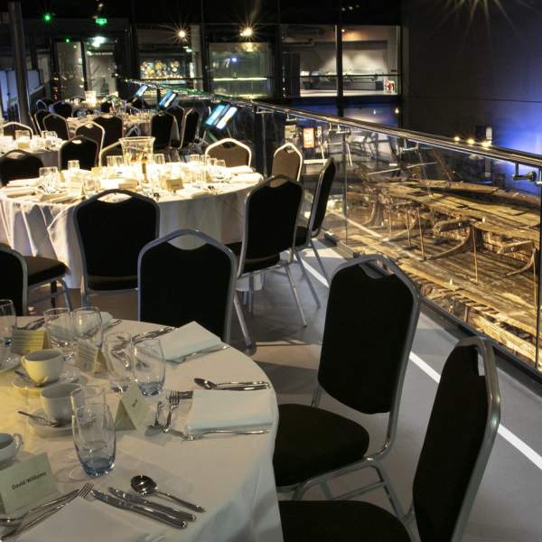 Tables set for an event at the Mary Rose museum, with the ship's hull on display behind