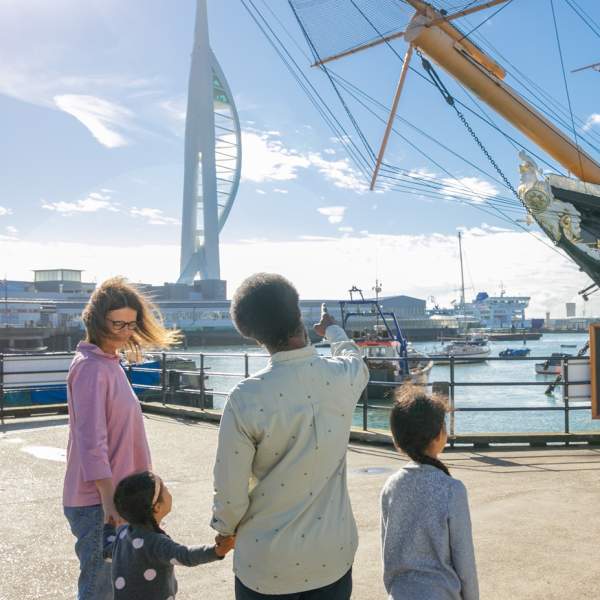 A family looks out at HMS Warrior, with the Spinnaker Tower in the background