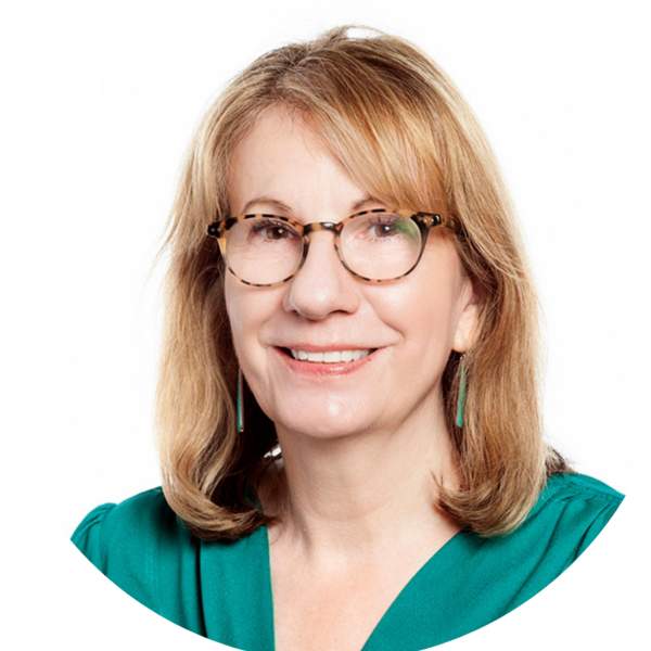 Professional headshot of woman with dark blonde hair and brown glasses smiling, wearing a green blouse.