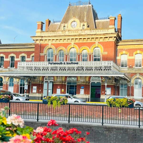 Photograph showing the front elevation of Portsmouth and Southsea Railway station with the sun shining on much of it.