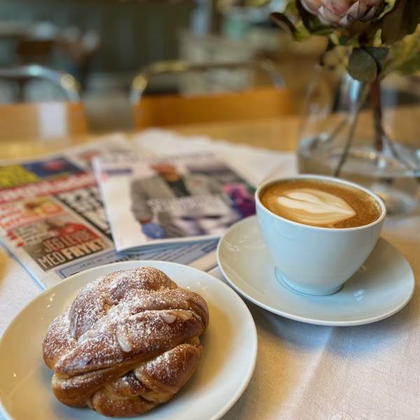 En kaffekopp og en bolle på ett bord