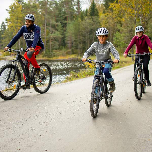 A family on a bike ride along a gravel road by a lake.