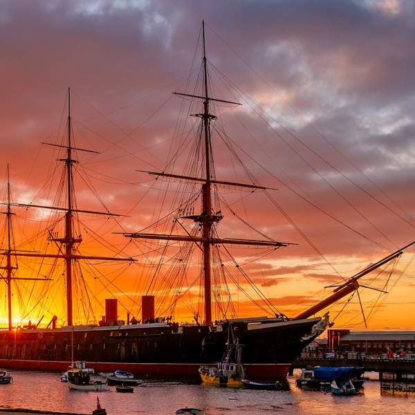 Photograph of HMS Warrior with a fiery dusk sky behind