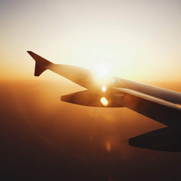 Photograph of an aeroplane wing with the sun setting behind it