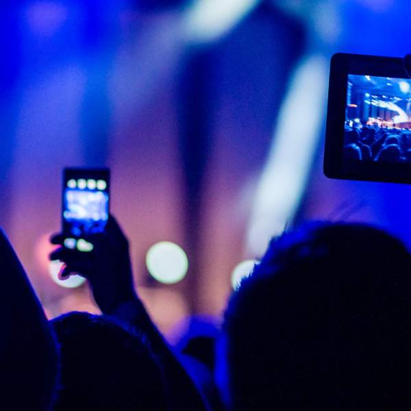 A crowd waving their arms at a concert in East Yorkshire whilst filming the act on stage on their mobile phones