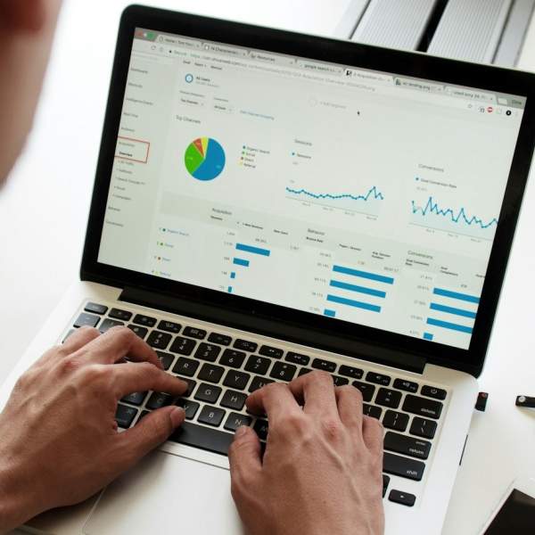 Person scrutinising data and graphs on a laptop