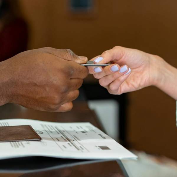 A receptionist hands over a keycard to a hotel guest