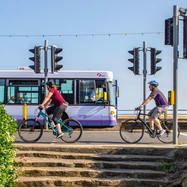 Photograph from Southsea Seafront, showing two cyclists going right to left from the viewer's perspective, whilst a First Solent bus passes in the opposite direction.