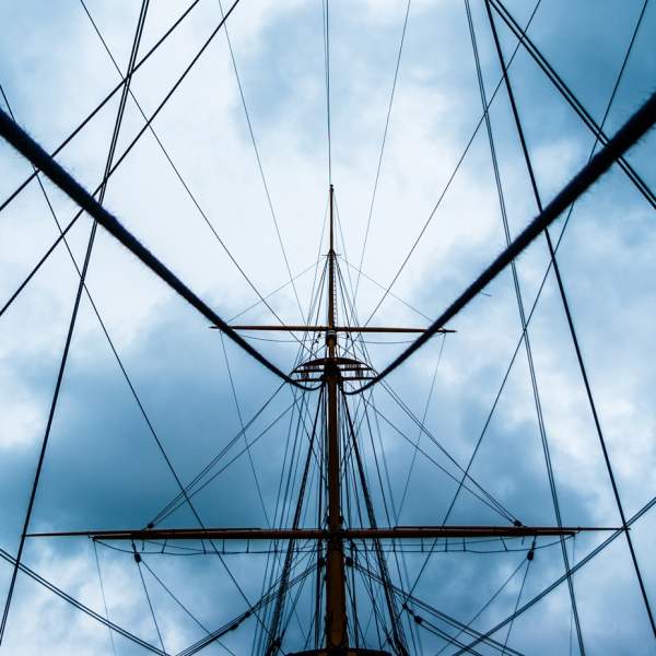 Rigging on a historic boat with an ominous, steely sky behind