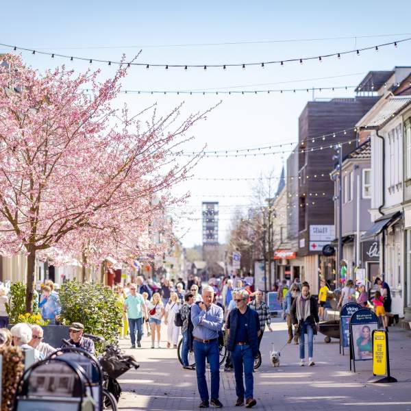 Mennesker som går i gågata og sitter på uteserveringen i Sarpsborg sentrum. Foto.