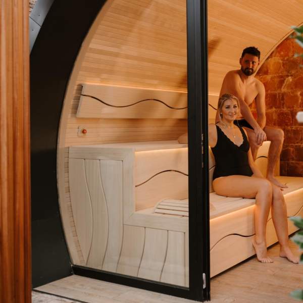 Couple sit in a sauna pod as part of a spa day experience