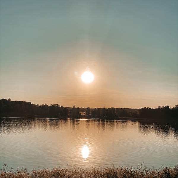 Solnedgang med refleksjon i vannet. Foto