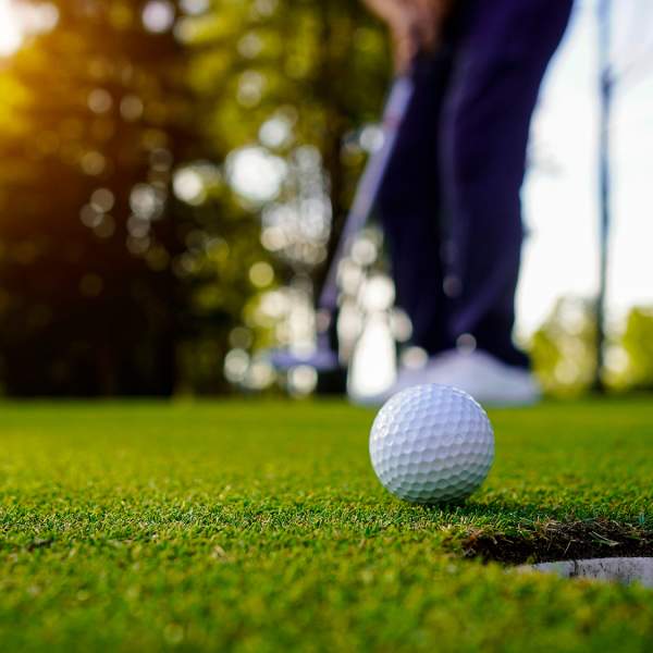 Golfball foran et hull på golfbanen