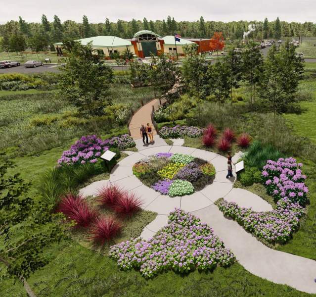 A 3D rendering of a landscape from above. A turtle shaped garden sits in the middle of the trail. A road sits to the right and a building with a green roof is in the background.