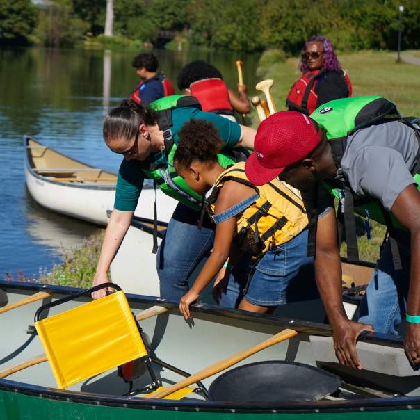 A family puts their canoe in the water before getting in to paddle.