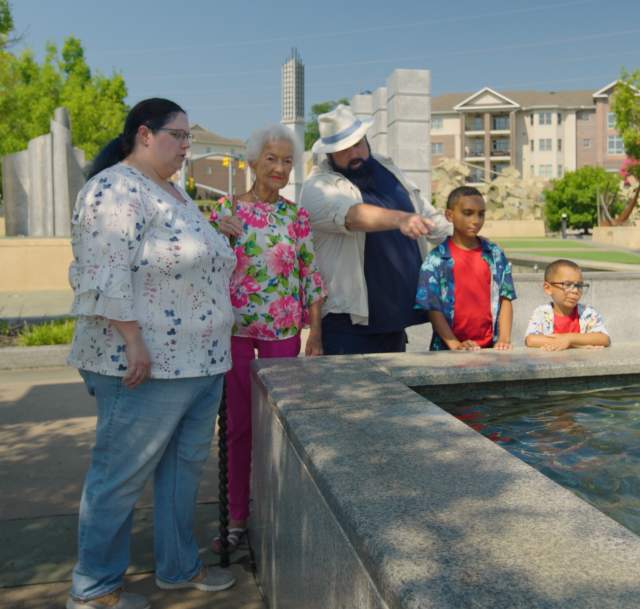 Multi-generational family gathered around the reflection pool in Fayetteville's Veterans' Park