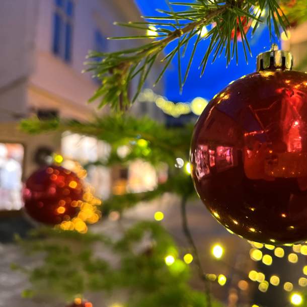 Nærbilde av rød julekule på juletre med julelys