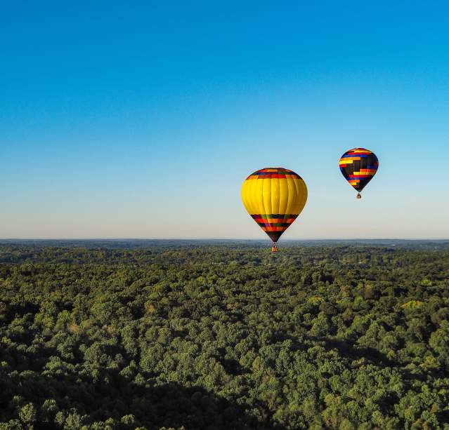 Two hot air balloons floating over Bloomington's rolling hills