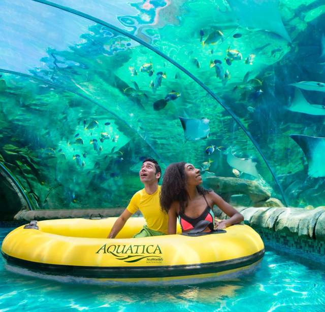 Man and woman in round float drifting through tunnel of stingrays.