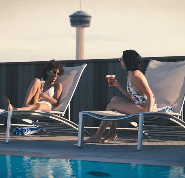 Two girls talking poolside on lounge chairs