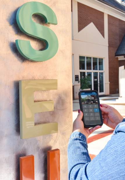 woman holding a phone showing an app by an attraction
