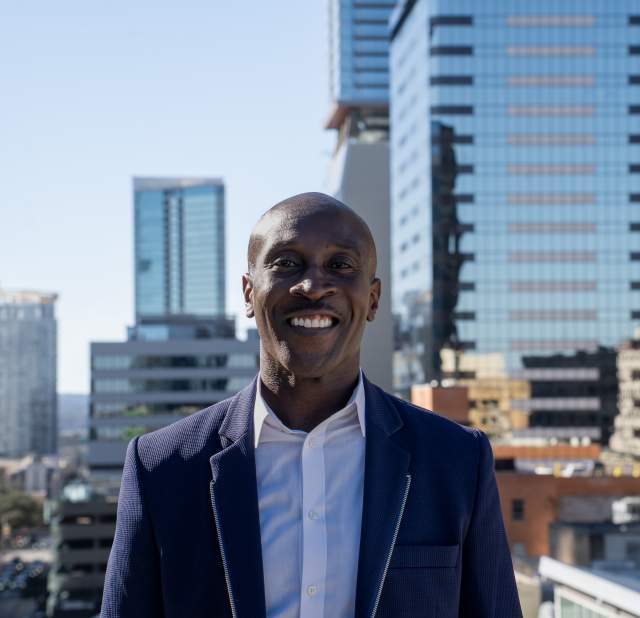 Davon Barbour wearing a suit smiling into the camera posing for a headshot.
