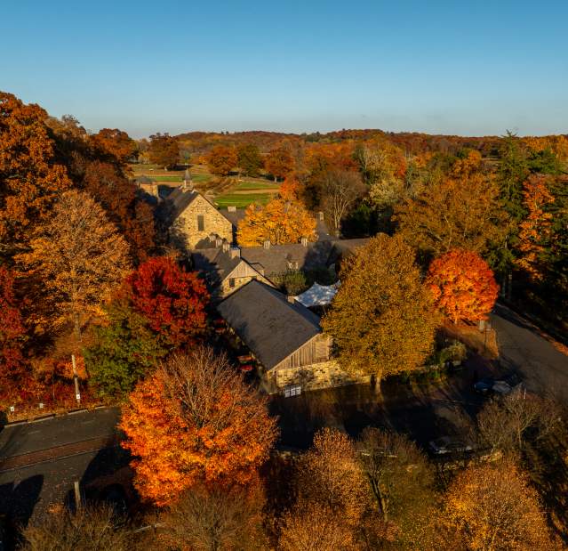 An aerial view of Stone Barns' buildings surrounded by orange and red fall foliage.