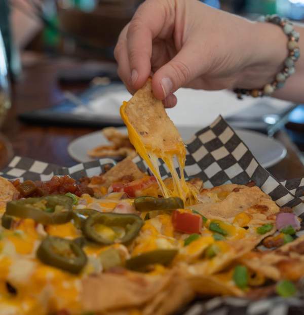 Hand grabbing from a plate of nachos