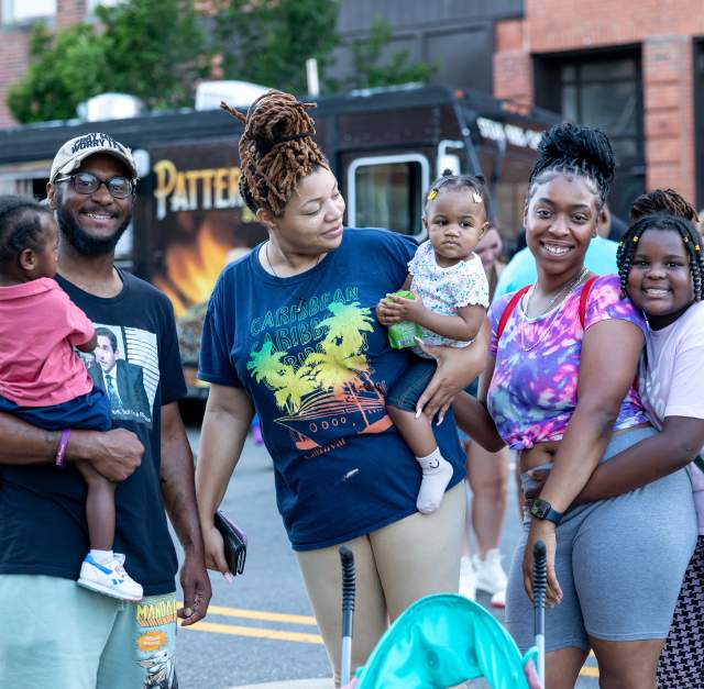 African-American family with three children, parents, and grandmother smiling at local festival