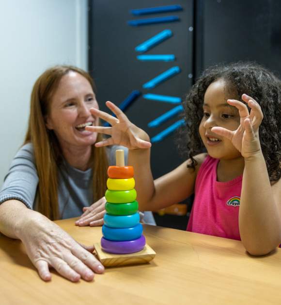A teacher and student playing with a colorful stacking toy