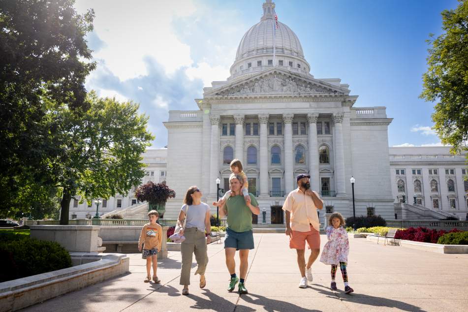Young children and adult tourists exploring the Capitol Building grounds and things to do in Madison WI