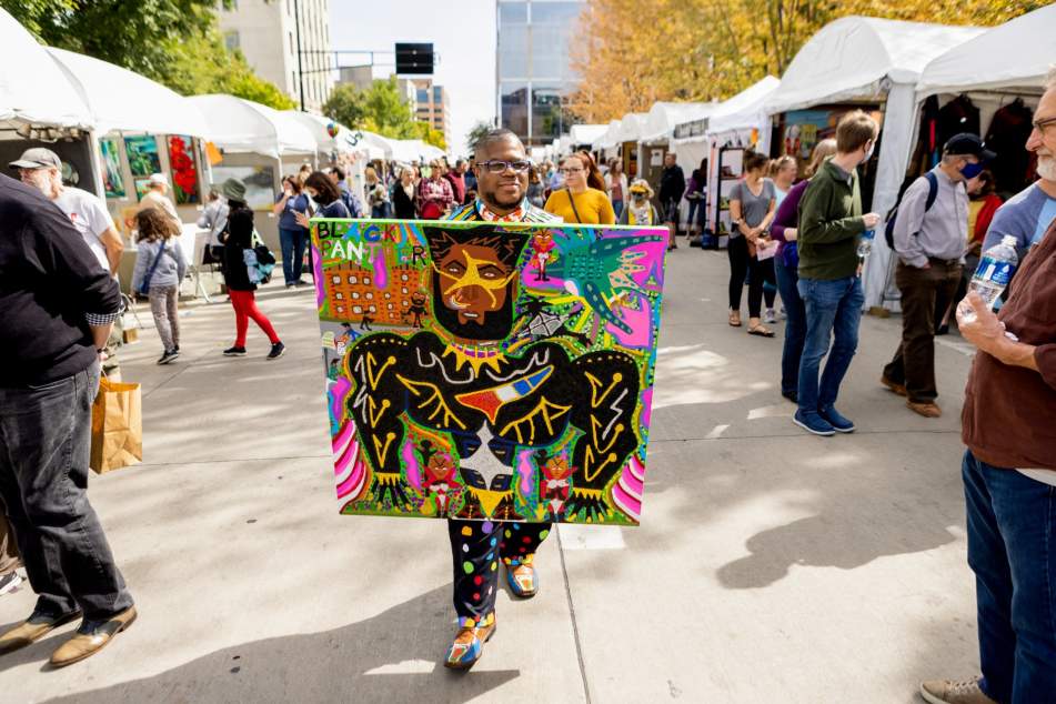 A black man walks down the center of Art Fair on the Square.