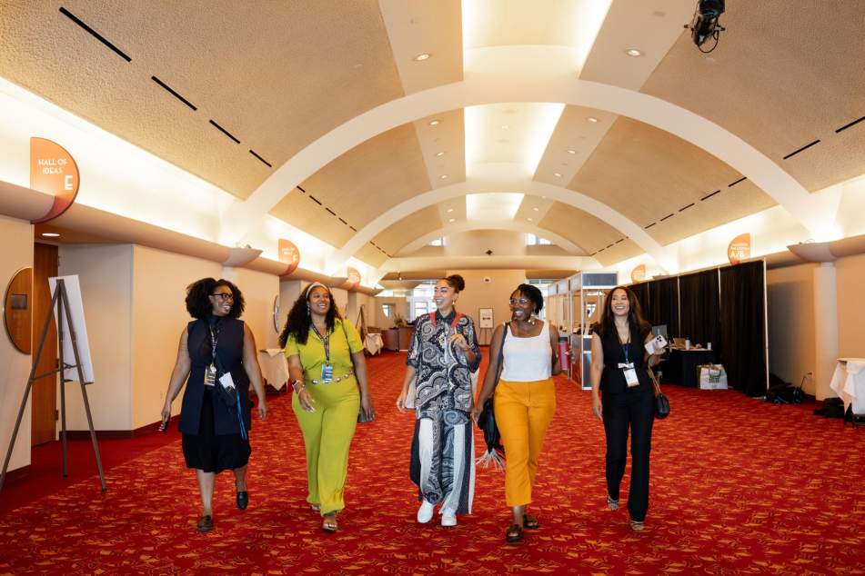 Five multicultural women walk through Monona Terrace Community and Convention Center during a mental health conference