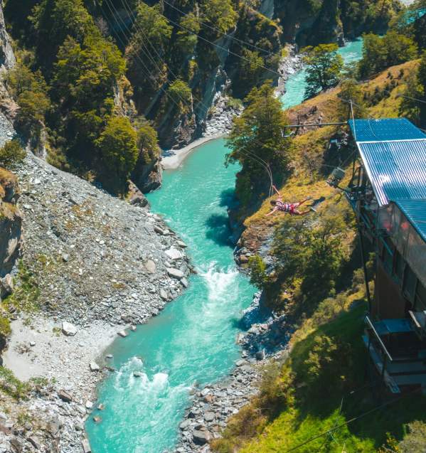 Far shot of a person doing the Canyon Swing with a river below