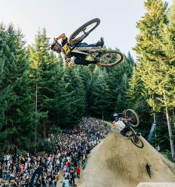 Two mountain bikers getting air over a big jump in front of a crowd at the Queenstown Bike Festival