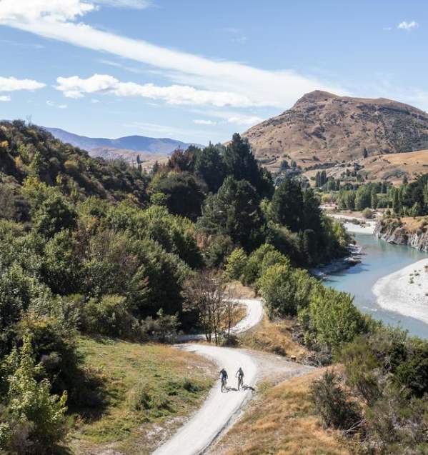 Aerial view of the Shotover Gorge Trail,with two bikers cycling next to a blue river in a Canyon