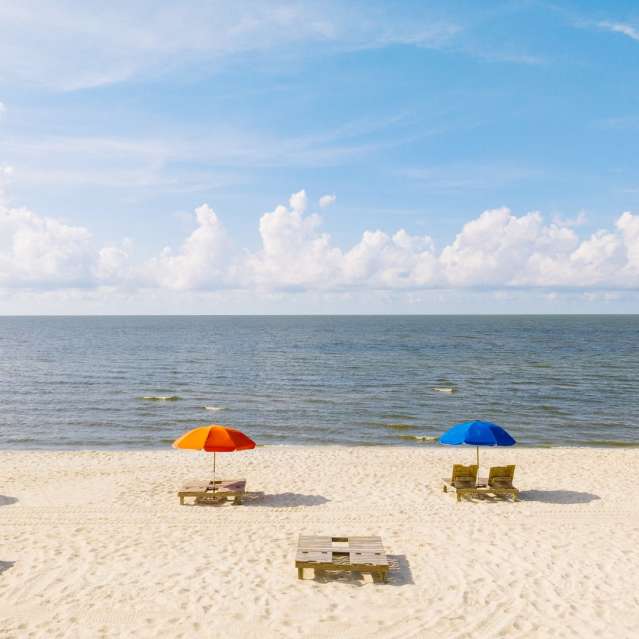 Biloxi Beach shoreline with multi-color umbrellas and chairs on a beautiful sunny day