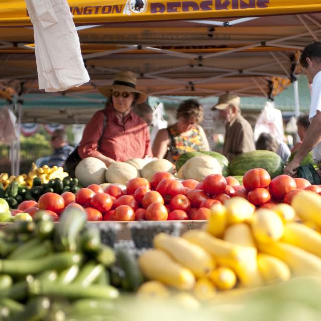people shopping for fruits and vegetables at a farmers market