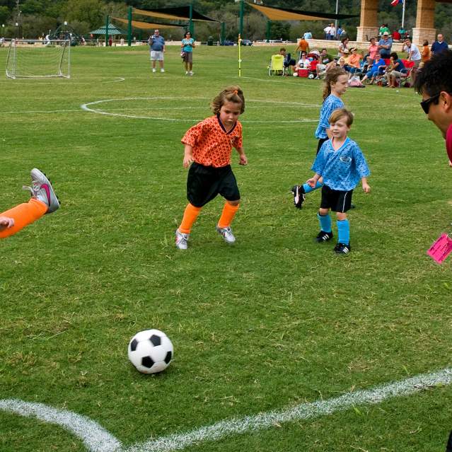 Young kids kicking ball at soccer tournament