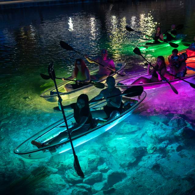 A group take a glow kayak tour on the San Marcos River