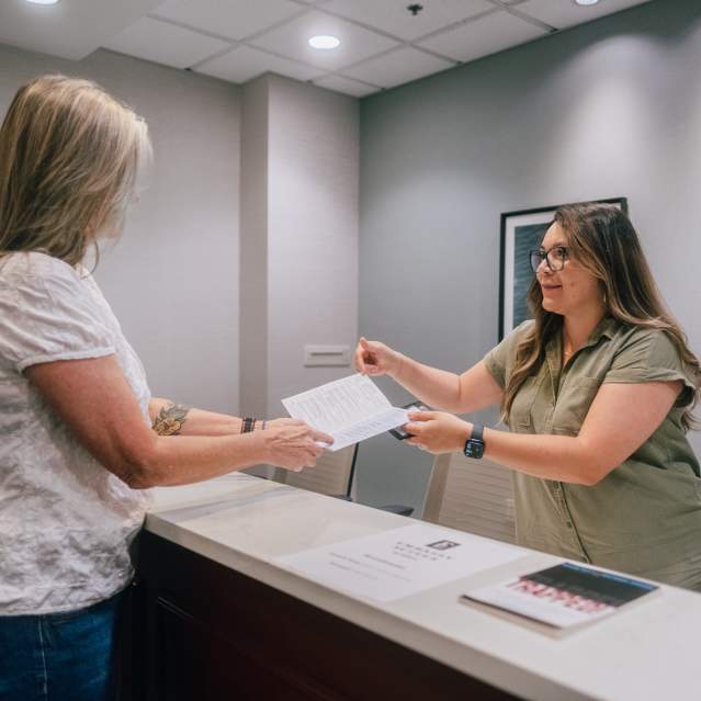 A woman helps a conference attendee find her way at the registration desk at the Embassy Suites Hotel & Conference Center in San Marcos, Texas.