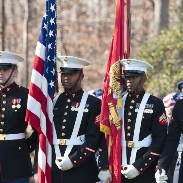 Marines in uniform holding flags for a ceremony