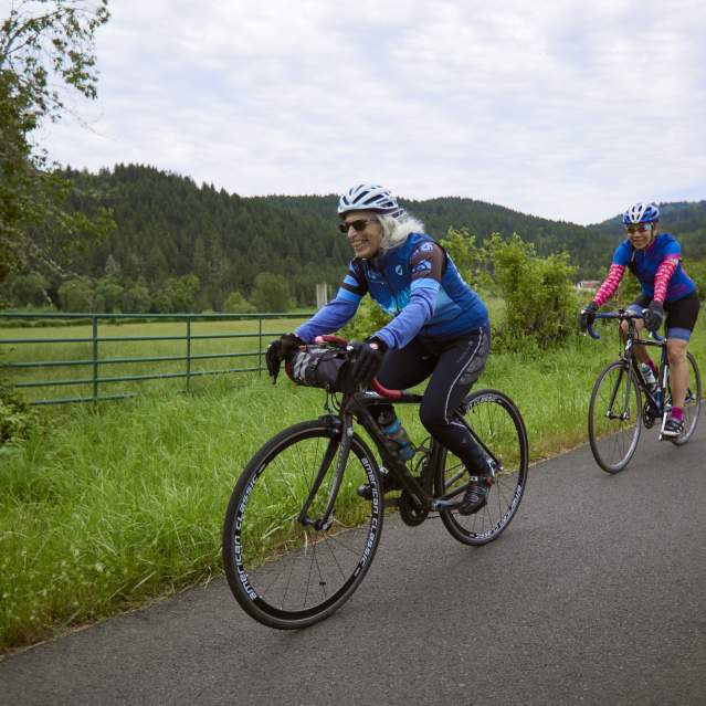 Three people riding single file along a country road.