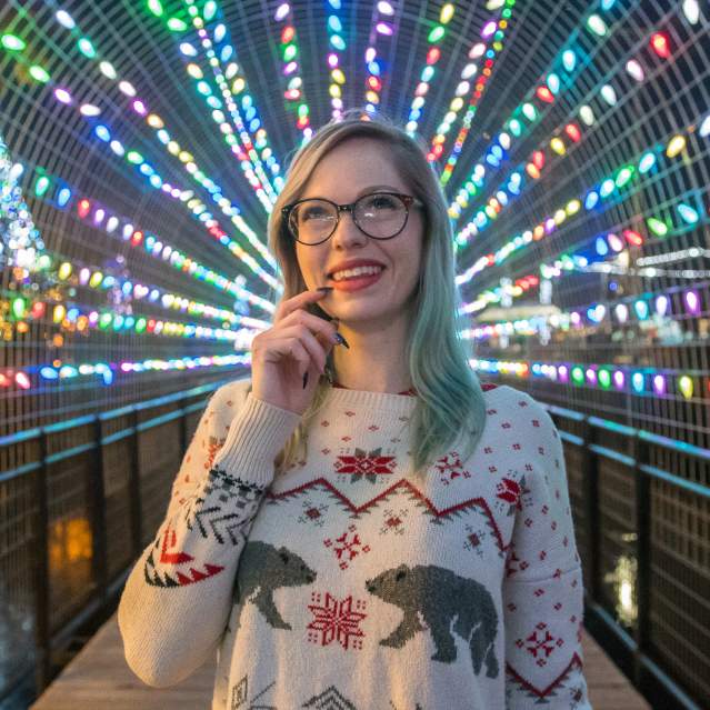 Woman under Christmas lights on bridge over river