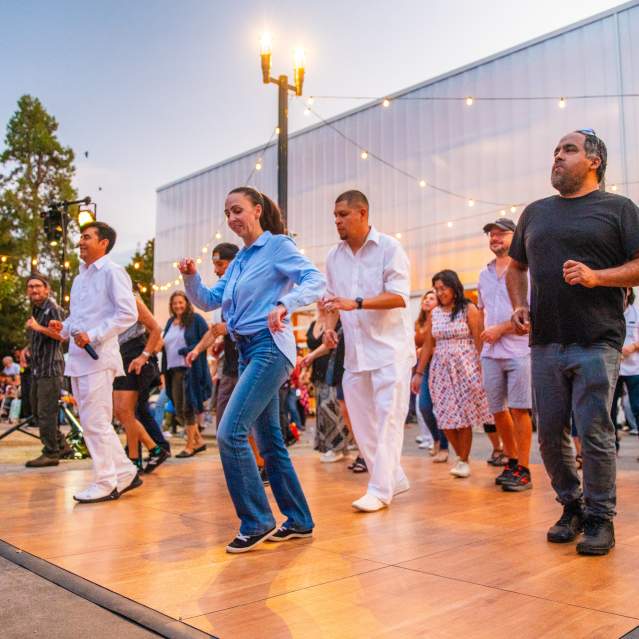 Dancers on an outdoor dance floor at twilight.