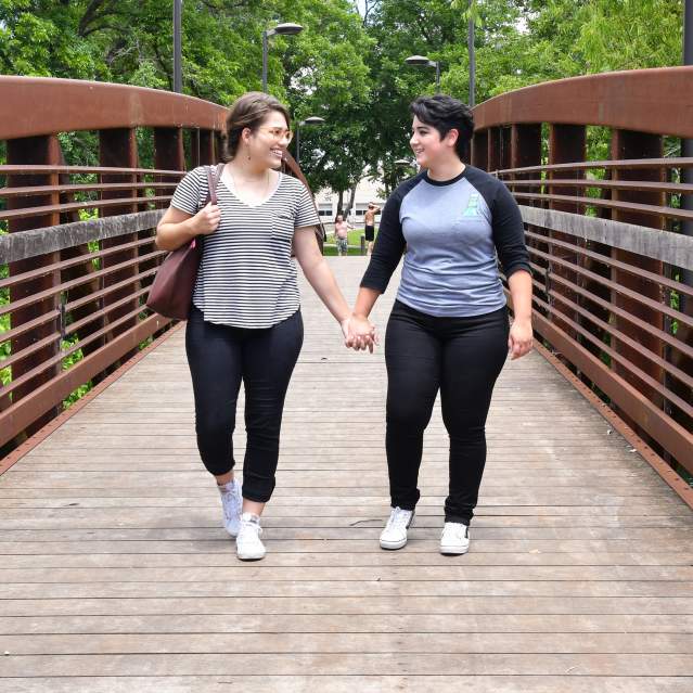 Two women holding hands walking over bridge