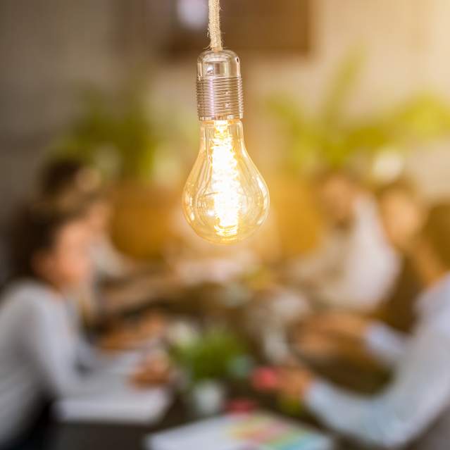 Out of focus group of people with lightbulb in foreground